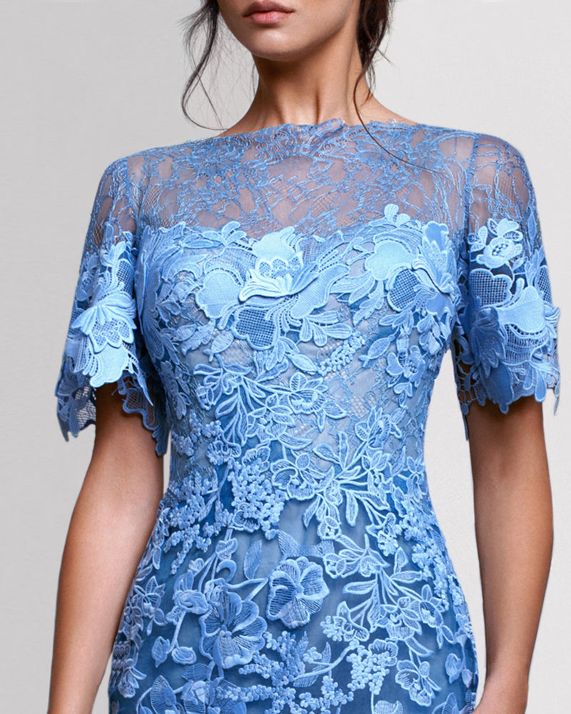 A close-up of a long blue evening dress featuring lace shoulders, an embroidered guipure bodice and short sleeves.