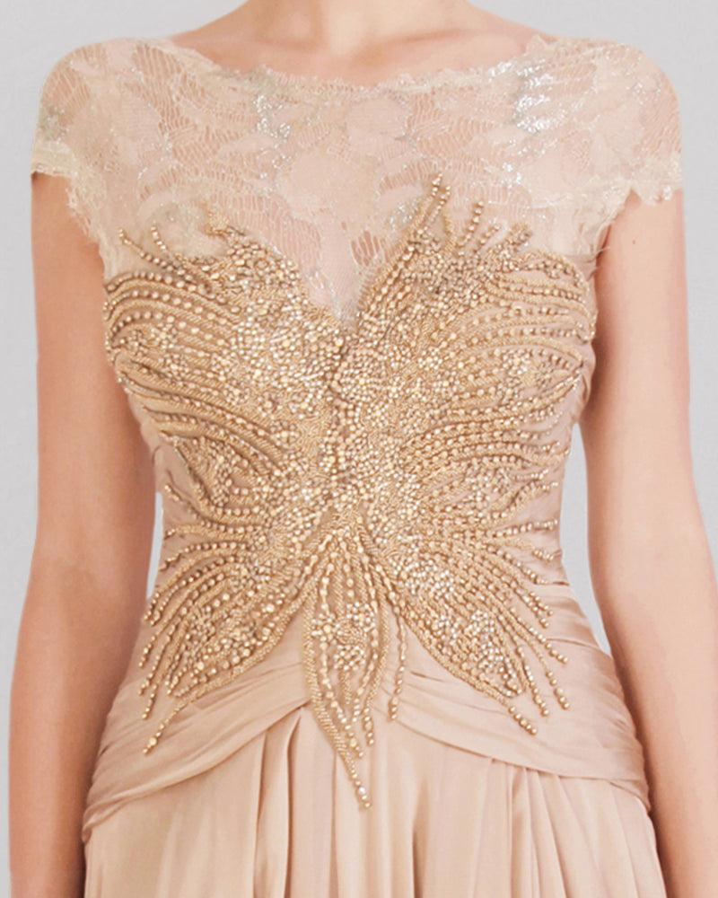 A close-up of a beige evening dress featuring a beaded lace bodice, short sleeves, and a gathered skirt.