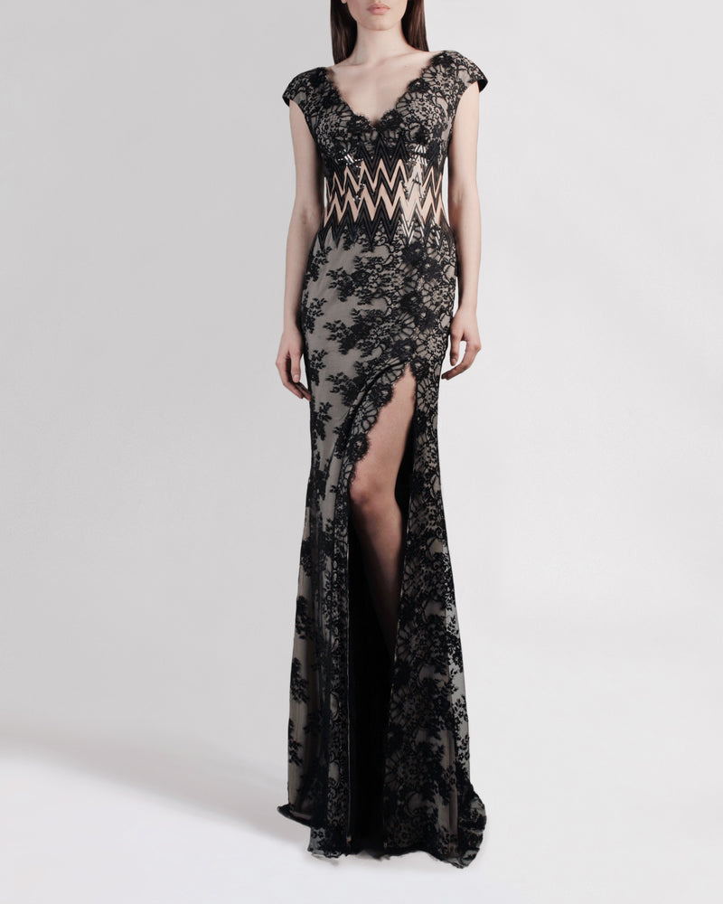 A long black lace evening dress with small sleeves and a zigzag see-through waist detailing.