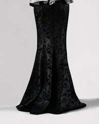 The back of a long black mermaid cut skirt in a shimmery mesh fabric.