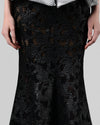 A close-up of a long black mermaid cut skirt in a shimmery mesh fabric.