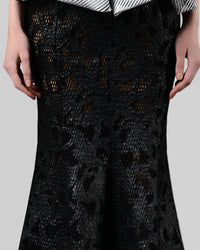 A close-up of a long black mermaid cut skirt in a shimmery mesh fabric.