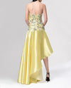 The back of a strapless yellow evening dress featuring  a lace bodice and a high-low hemline.