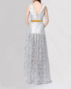 The back of a high-low evening gown in a shimmery silver fabric featuring a fitted bodice, and a contrasting mustard-yellow velvet belt.