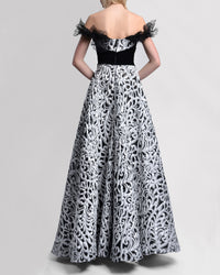 The back of an A-line off-the-shoulders long evening gown with intricate black lace sleeve details and waist, and a striking black-and-silver contrasting fabric.