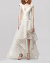 An off-the-shoulders asymmetrical beige evening dress featuring a fitted bodice and lurex organza jacquard skirt.