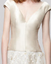 A close-up of an off-the-shoulders beige evening dress featuring a fitted bodice and lurex organza jacquard skirt.