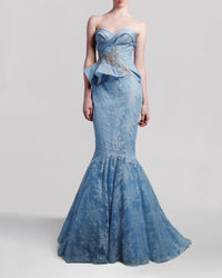 A long blue strapless evening gown featuring a draped bodice, embroidered embellishments, and a mermaid-cut skirt.