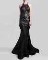 A halter-neck fitted black evening gown in lace and rose patterned sequins fabric, and a sheer floor-length skirt with a flowing train.