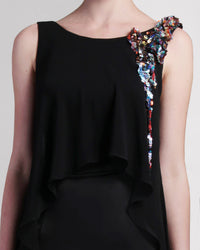 A close-up of a black evening dress with a chiffon overlay, featuring beading details on one shoulder.