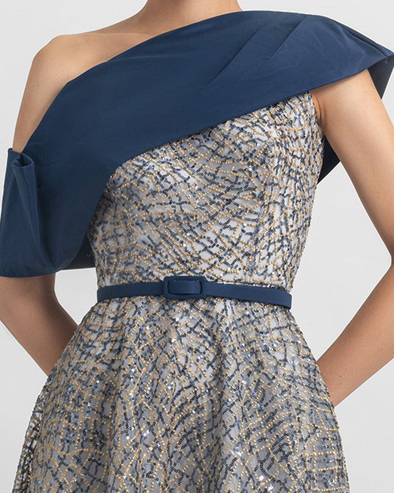 A close-up of an A-line beaded evening dress with an asymmetrical draped neckline, paired with a detachable navy belt.